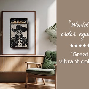 May include: A black and white illustration of a skeleton wearing a cowboy hat and smoking a cigarette. The illustration is printed on a matchbox. The matchbox is framed and hanging on a wall.