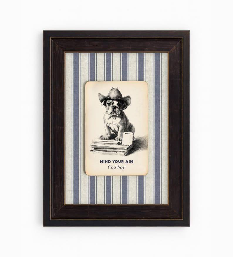 May include: Framed artwork featuring a bulldog wearing a cowboy hat. The black and white illustration is set against a blue and white striped background. The text "MIND YOUR AIM Cowboy" is printed below the dog.