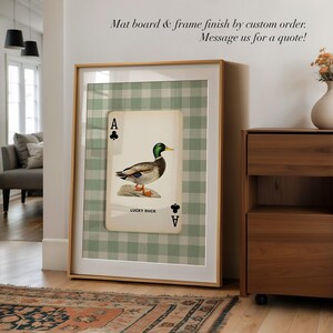 May include: A framed wall art print featuring an Ace of Clubs playing card design with a mallard duck illustration, the text LUCKY DUCK, and a green and white gingham background. The print includes the text Mat board & frame finish by custom order. Message us for a quote!