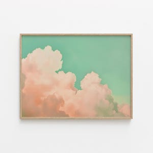 May include: A framed print of a pastel pink and orange cloud formation against a light teal sky.