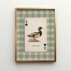 A vintage inspired Ace of Clubs playing card design with a botanical illustration of a mallard duck and the words "Lucky Duck" at the bottom of the card. Set against a green and oatmeal colored gingham patterned linen texture. Farmhouse decor.