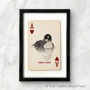 Puede incluir: Una impresi&oacute;n enmarcada de 30,48 cm por 45,72 cm con un dise&ntilde;o de carta de as de corazones. La tarjeta tiene un fondo crema con una ilustraci&oacute;n en blanco y negro de un colimbo, corazones rojos, la letra A y el texto REBEL LOON en rojo.