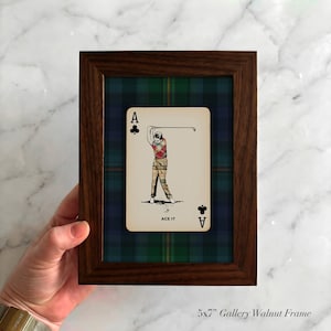 May include: A framed playing card featuring a golfer in action, labeled "ACE IT". The card is set against a green, blue, and black plaid background within a 5x7 inch walnut frame. The frame is a gallery style.