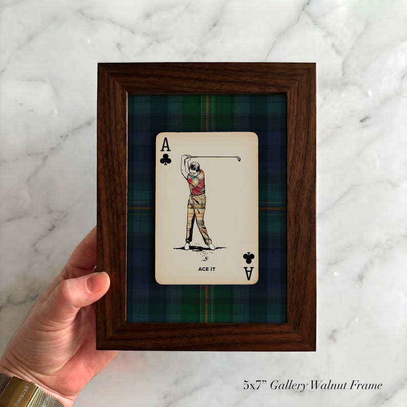 May include: A framed playing card featuring a golfer in action, labeled "ACE IT". The card is set against a green, blue, and black plaid background within a 5x7 inch walnut frame. The frame is a gallery style.