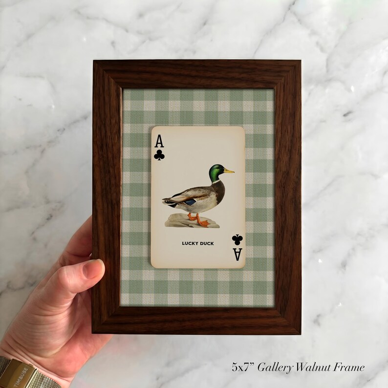 May include: A 5x7 inch dark walnut wood frame containing a playing card with an illustration of a mallard duck. The card features the text 'A' and club symbols in the corners, with 'LUCKY DUCK' printed below the duck on a green gingham background.
