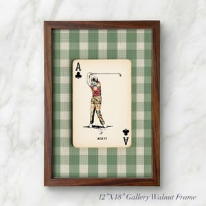 K&ouml;nnte beinhalten: Ein 30,48 cm mal 45,72 cm gro&szlig;er Walnussrahmen mit einer Spielkarte, die einen Golfer, den Text ACE IT und Kreuz-Symbole zeigt. Die Karte liegt auf einem gr&uuml;n-wei&szlig;en Vichy-Karo-Hintergrund. Der Rahmen ist mit 12"X18" Gallery Walnut Frame beschriftet.