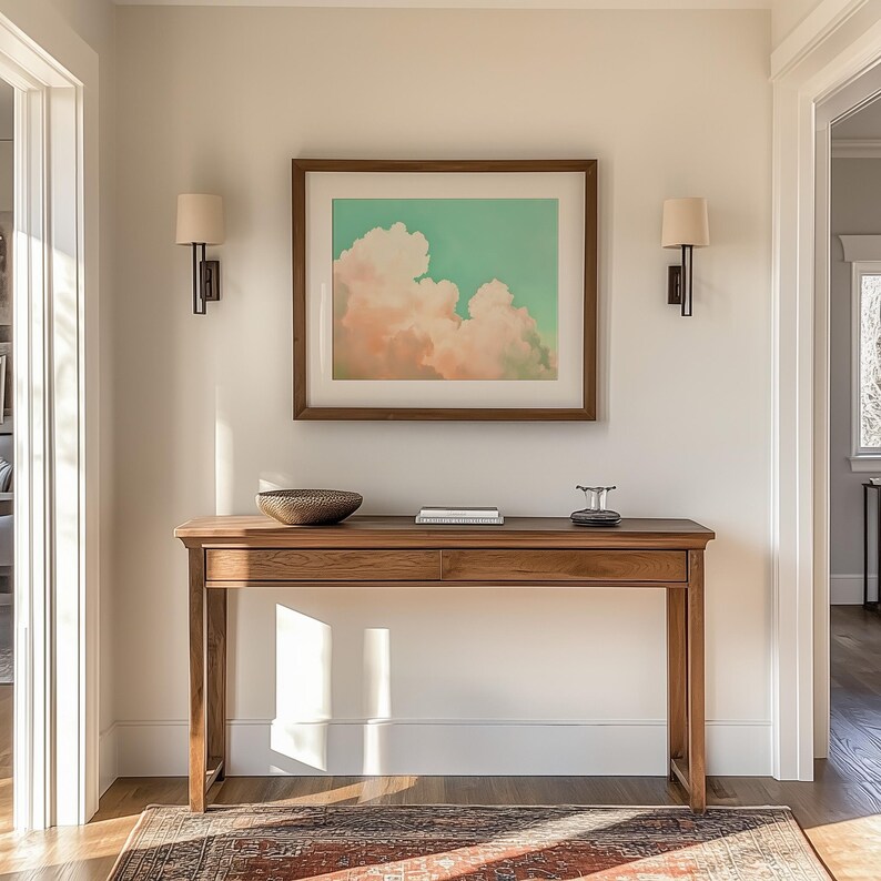 Panoramic wall art featuring billowing pink clouds against a soft sage green sky, creating airy Western big-sky artwork ideal for farmhouse, ranch, or modern bedroom décor. Shown here finished with a white mat and brown framed giclée fine art paper print.