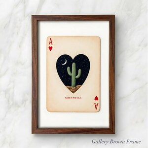 May include: A framed playing card featuring the Ace of Hearts. The card's heart shape contains a desert cactus under a starry night sky and a crescent moon. The text "MADE IN THE U.S.A." is printed at the bottom.