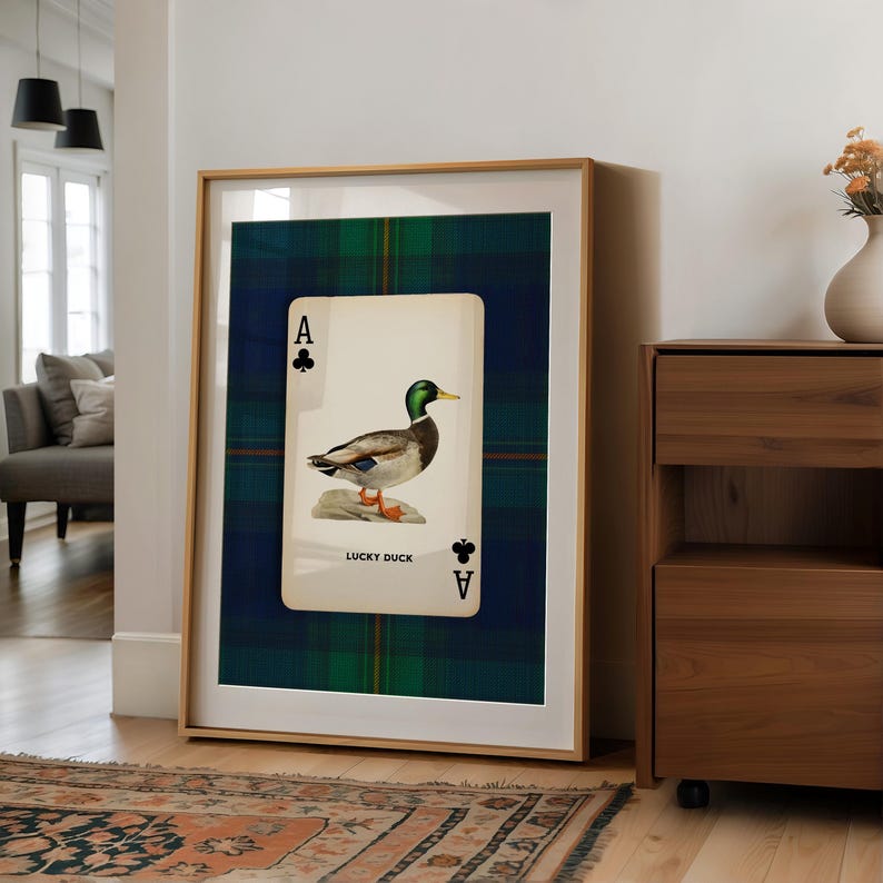 May include: Framed art print featuring a playing card design with a duck illustration. The card is the Ace of Clubs, with the words "LUCKY DUCK" below the duck image. The background is a green and blue plaid pattern.