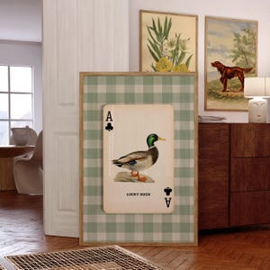 May include: A rectangular wall art print featuring a light green and white gingham background. Centered is a large playing card graphic with an Ace of Clubs symbol, a detailed illustration of a mallard duck, and the text LUCKY DUCK.