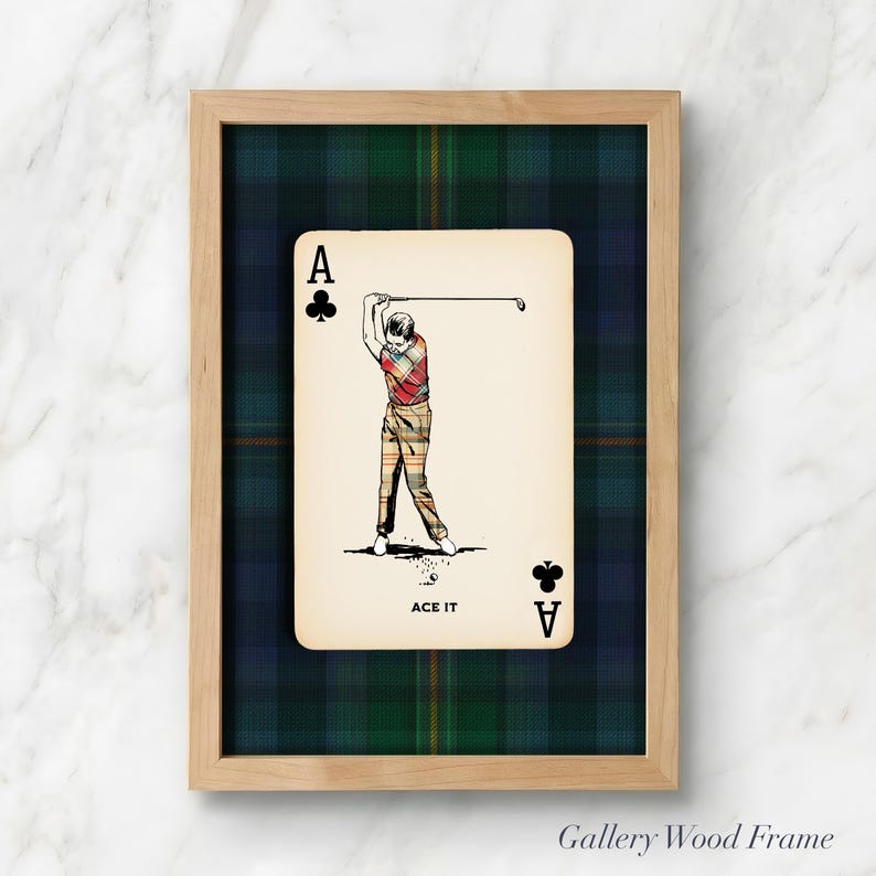 May include: Framed artwork featuring a playing card with a golf theme. The card is the Ace of Clubs, with a golfer in mid-swing. The background is a green and blue plaid pattern, and the frame is light wood. The text "ACE IT" is at the bottom.