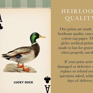 May include: A playing card design featuring a mallard duck with a green head and orange feet standing on a rock, labeled LUCKY DUCK with club symbols. The adjacent text reads HEIRLOOM QUALITY, describing archival giclee prints on canvas and cotton rag paper.