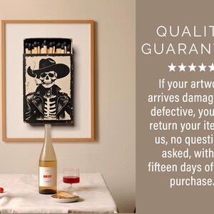 May include: A framed print of a matchbox with a skeleton cowboy wearing a hat and smoking a cigarette. The print is hanging on a wall above a table with two bottles of wine and a glass of wine.