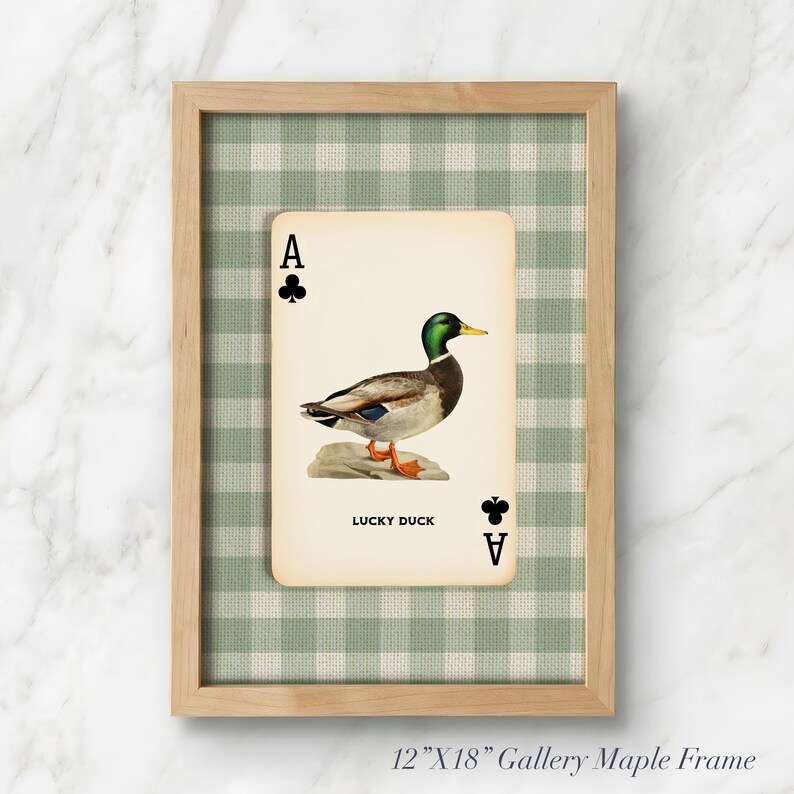 May include: A 12-inch by 18-inch maple wood frame containing a print of an ace of clubs playing card featuring a mallard duck illustration and the text LUCKY DUCK. The background behind the card is a light green and white gingham fabric pattern.