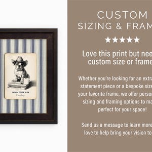 May include: Framed artwork featuring a bulldog wearing a cowboy hat, with the text "MIND YOUR AIM Cowboy." The artwork is set against a blue and white striped background, encased in a dark brown frame. A unique piece for home decor.