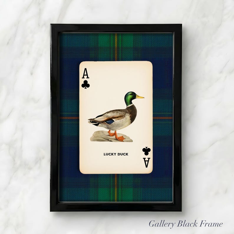 May include: A framed print featuring a playing card with an illustration of a duck. The card is set against a blue and green plaid background within a black frame. The card reads "LUCKY DUCK" and has the Ace of Clubs.