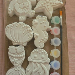 Puede incluir: Kit de manualidades con formas de criaturas marinas blancas: tortuga, estrella de mar, caballito de mar, concha, cola de sirena y medusa. Incluye pinturas de varios colores y un pincel. Las formas están listas para pintar.