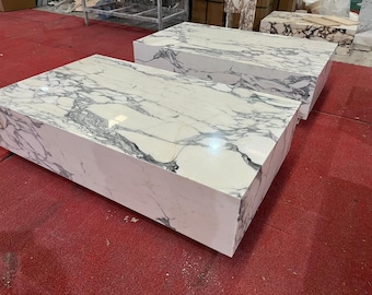 May include: Two white marble coffee tables with gray veining. The tables are rectangular and have a modern design.
