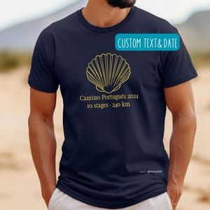 May include: A navy blue short-sleeve t-shirt featuring a gold outline of a scallop shell. Below the shell, the text reads Camino Portugués 2024, 10 stages - 240 km. A teal rectangular graphic at the top right contains the text CUSTOM TEXT & DATE.