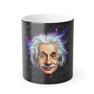May include: A black coffee mug featuring a portrait of Albert Einstein with white hair and a mustache. The mug has equations and formulas in white on a black background, with colorful swirls around Einstein's head.