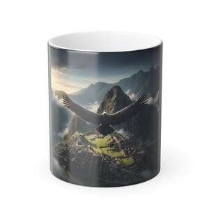 Op de afbeelding: Witte keramische mok met een gedetailleerde afbeelding van Machu Picchu en een vogel in vlucht. Het ontwerp toont een berglandschap met wolken en een heldere lucht, wat een schilderachtige scène creëert.