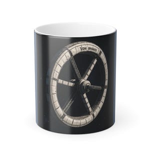May include: A black ceramic mug with a detailed illustration of a space station wheel and the text "Von Brann". The design is in white and grey, set against a dark, starry background. The mug has a white interior.