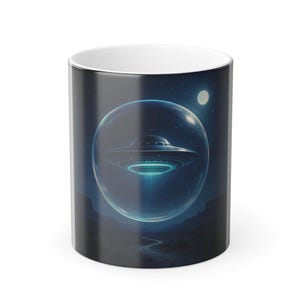 Puede incluir: Taza de cerámica blanca con una ilustración detallada de un OVNI dentro de una esfera brillante. El diseño incluye un cielo nocturno con una luna y un paisaje. La taza tiene un esquema de color negro y azul.