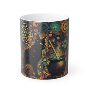Puede incluir: Taza de cerámica con la silueta de un gato negro, un caldero y una varilla para remover. La taza tiene un fondo colorido con diseños geométricos y celestiales en tonos naranja, verde y azul. El interior de la taza es blanco.