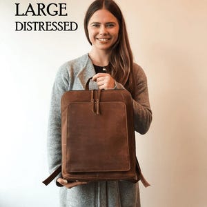 May include: A large, distressed brown leather backpack with a front pocket and a top handle. The backpack has adjustable straps and a zipper closure. The words "LARGE DISTRESSED" are printed in black at the top left.