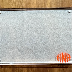 May include: A clear acrylic picture frame with a white mat and a red monogram "AND" in the bottom right corner.