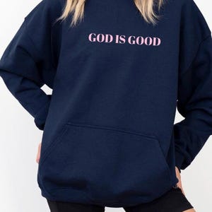 May include: A navy blue hoodie with a pink graphic that says "GOD IS GOOD".