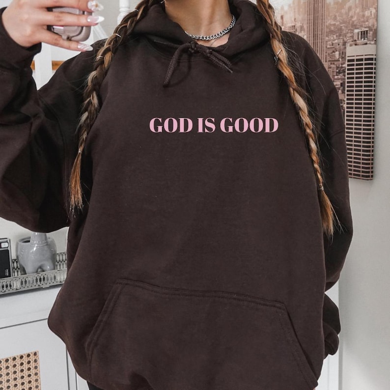 May include: A brown hoodie with a pink graphic that says "GOD IS GOOD".