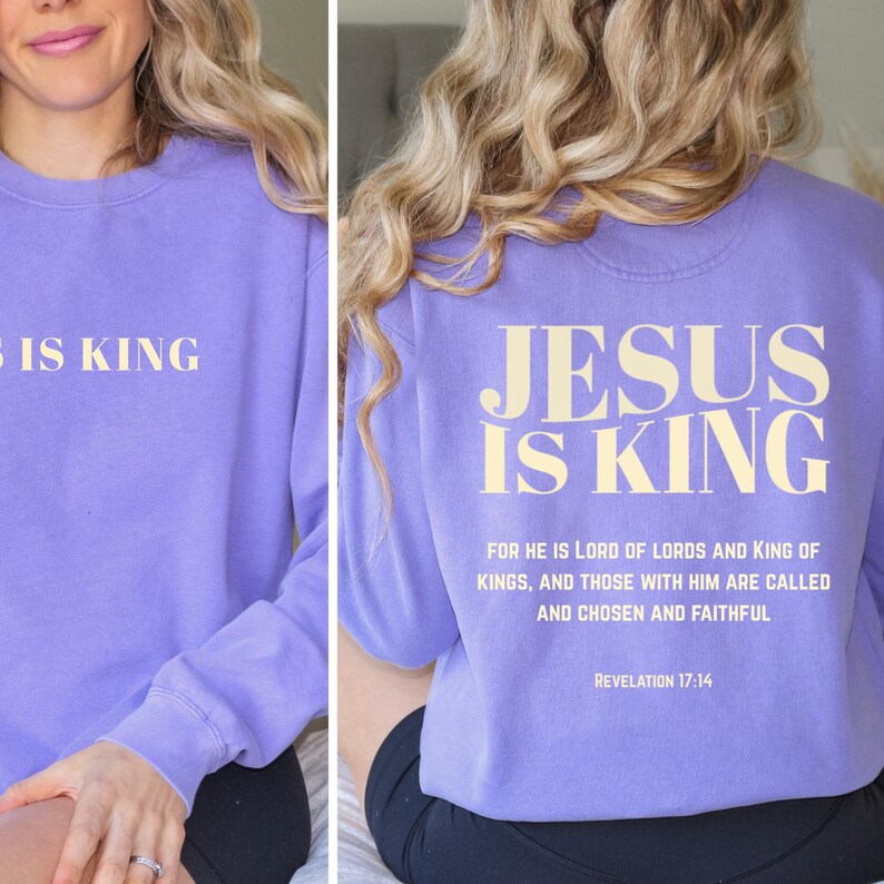 May include: A lilac-colored sweatshirt with the text "JESUS IS KING" printed on the front and back. The back of the sweatshirt also features a Bible verse from Revelation 17:14.