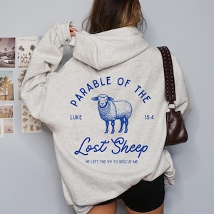 May include: Light gray hoodie with a blue graphic of a sheep and the text "Parable of the Lost Sheep" with the scripture reference Luke 15:4. The hoodie has a drawstring hood and long sleeves.