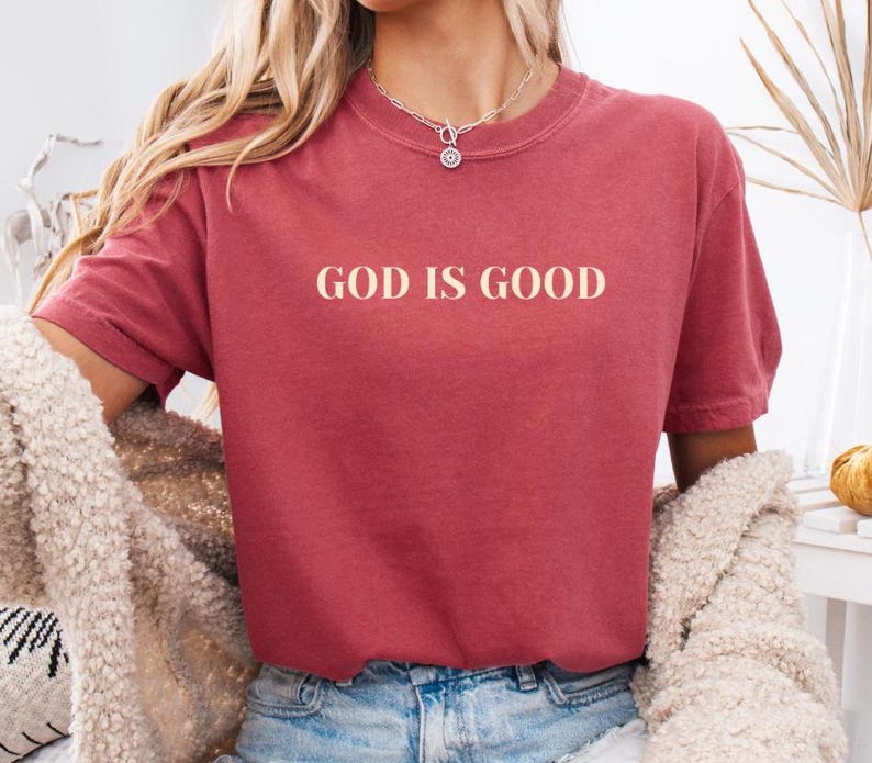 May include: A red t-shirt with the text "GOD IS GOOD" printed in a cream color on the front.