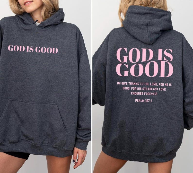 May include: A dark gray hooded sweatshirt with the phrase "God is Good" printed in pink on the front and back. The back also includes the text "Oh give thanks to the Lord, for he is good, for his steadfast love endures forever! Psalm 107:1."