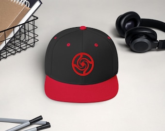 May include: A black and red baseball cap with a red swirl design on the front.