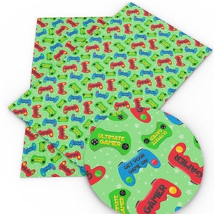 May include: Green fabric with a repeating pattern of colourful video game controllers and stars. The fabric also has the text "Ultimate Gamer" and "Get your game on!" printed on it.