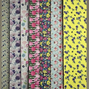 May include: Eight different fabric samples with floral patterns. The fabrics are in various colours, including purple, blue, pink, yellow, and green. The fabrics are arranged in a row from left to right, labelled A through G.