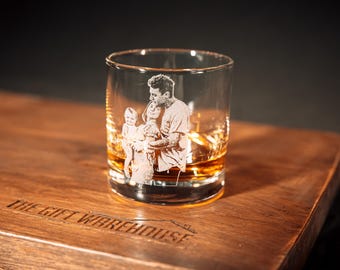 Peut inclure: Un verre transparent gravé au laser en blanc représentant une personne tenant un enfant. Le verre contient un liquide ambré et repose sur une planche en bois portant l'inscription THE GIFT WAREHOUSE gravée sur la surface.