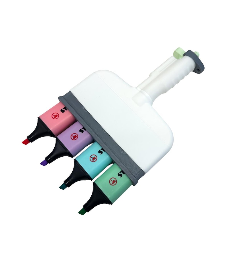 Puede incluir: Una herramienta resaltadora m&uacute;ltiple de pl&aacute;stico blanco con cuatro marcadores Stabilo integrados en tonos pastel rosa, morado, azul y verde. El dispositivo tiene un mango central y un marco gris que sujeta los marcadores, cada uno con punta negra y un logotipo de cisne.