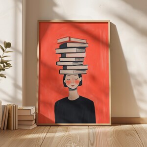 Pode incluir: Uma impressão de arte emoldurada com uma pessoa com uma pilha de livros equilibrada na cabeça contra um fundo vermelho vibrante. A pessoa está vestindo uma blusa preta. A obra de arte tem um estilo minimalista com uma paleta de cores quentes.