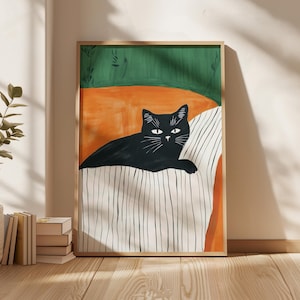 May include: A framed art print depicting a black cat lounging on a striped cushion. The background features orange and green blocks. The artwork is in a wooden frame and is displayed on a wall.