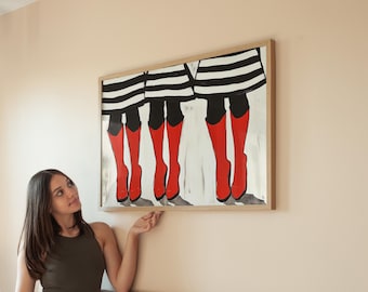 May include: A framed painting of three women wearing black and white striped skirts and red boots. The painting is on a white wall.