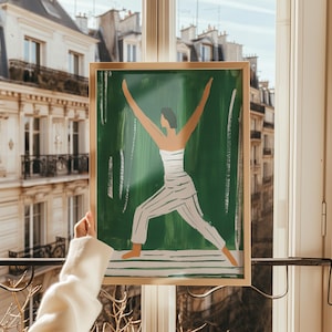 May include: A framed illustration of a person in a yoga pose with arms raised, against a green background. The person is wearing a white and black striped outfit.