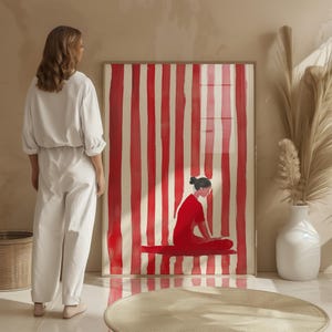 Puede incluir: Una pintura enmarcada de una mujer de rojo sentada sobre un fondo de rayas blancas y rojas.