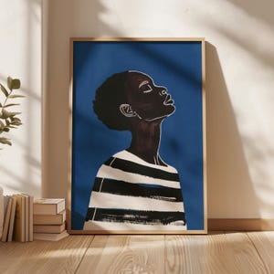 以下が含まれることがあります： 青い背景に、黒と白のストライプのシャツを着た、黒い肌の人物の額縁入りイラスト。人物は上を見上げていて、目は閉じている。