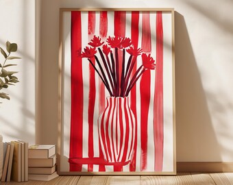 May include: A framed art print featuring a watercolor painting of a vase with red and white stripes, holding red flowers with dark stems. The background has vertical red stripes. The frame is a light brown color.