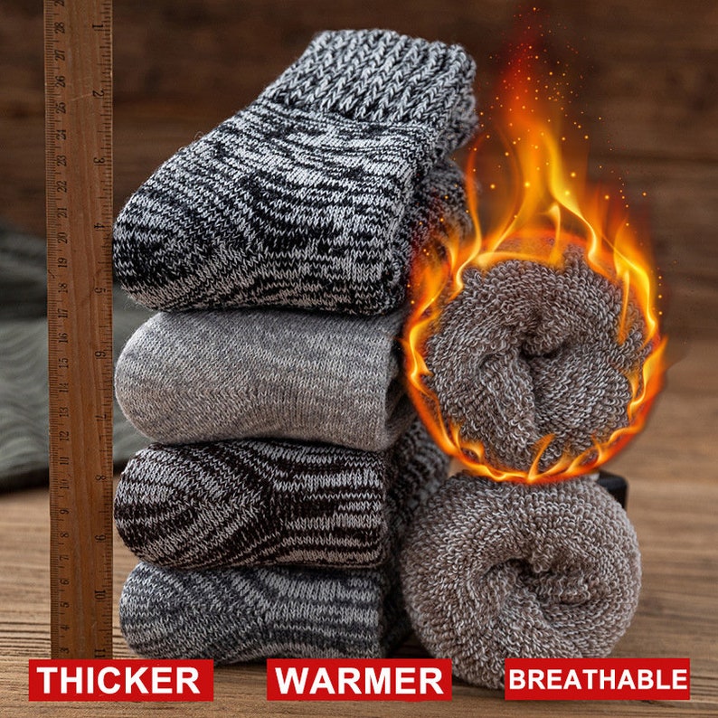 May include: A stack of four pairs of grey and black thermal socks. The socks are thick and warm, and the text "THICKER WARMER BREATHABLE" is printed below the socks.