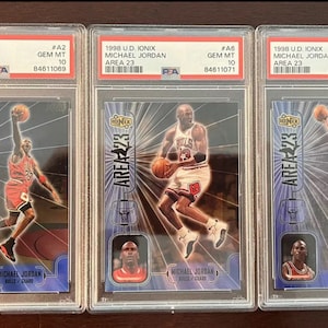 May include: Three graded trading cards featuring Michael Jordan, each card is in a protective case and graded as Gem Mint 10. The cards are from the 1998 U.D. Ionix Area 23 series.